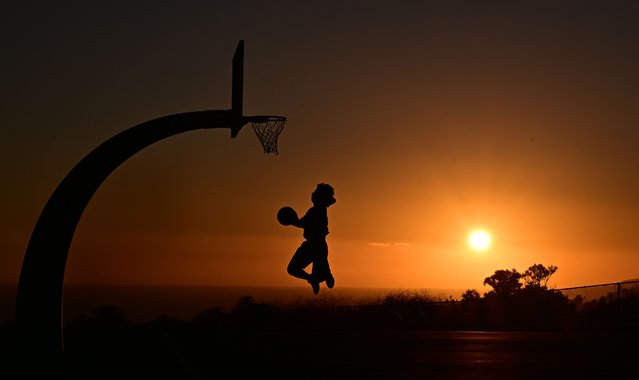 A boy shoots hoops at sunset on August 19, 2025 in San Pedro, California. The National Weather Service issued an extreme heat warning for parts of Los Angeles County which will be in effect from August 21 into the weekend, with temperatures expected to reach 110 degrees in some areas. (Photo by Frederic J. Brown/AFP Photo)