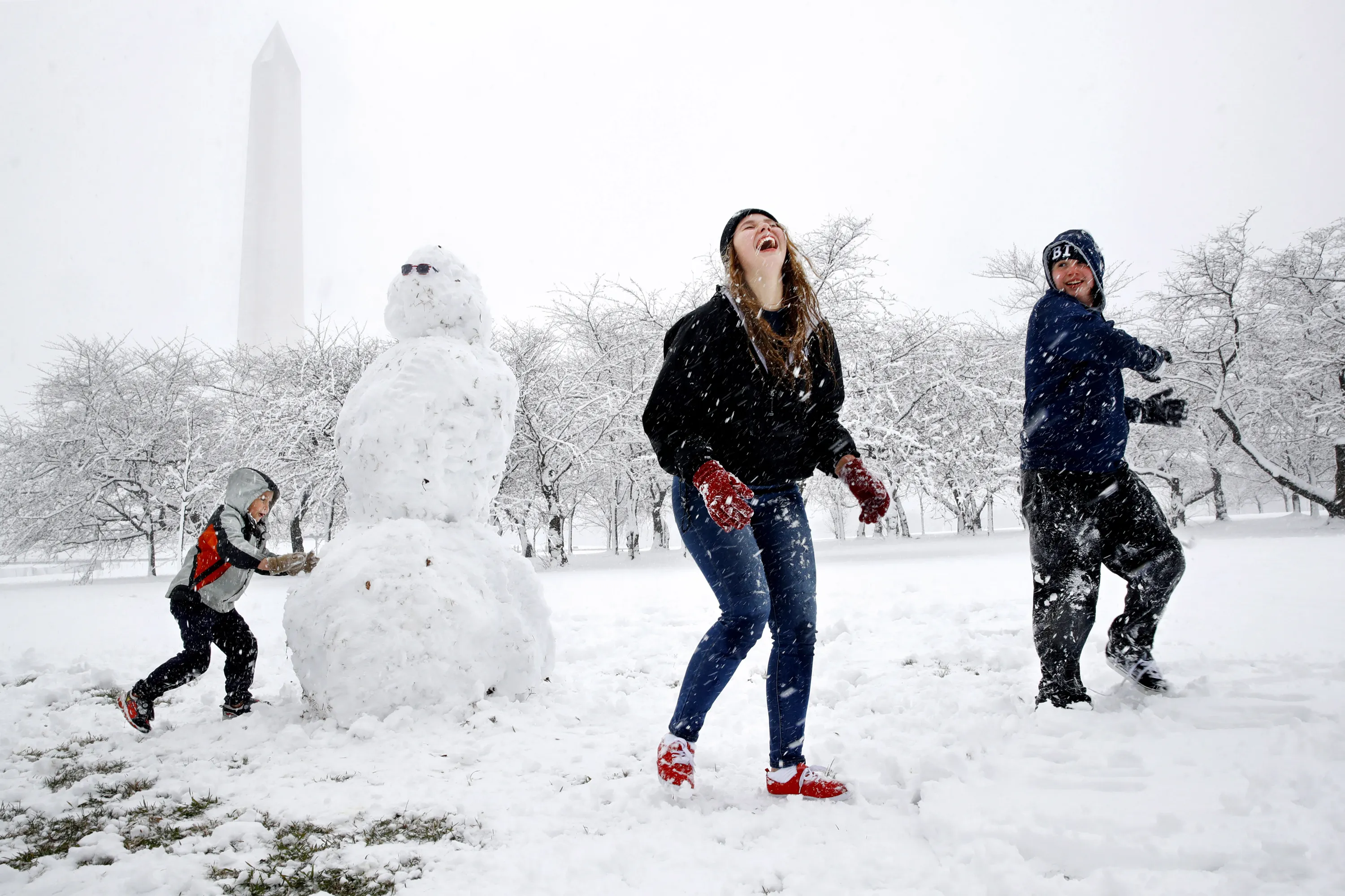 works on a snowman as his siblings, Amanda Lariscy, 17, and Blaze Lariscy, ...