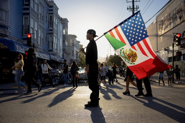 Jean Carlo Bonilla holds a flag combining the flags of Mexico and the U.S. at a lowrider car show celebrating lowriding culture and supporting immigration, in San Francisco, California, U.S., September 20, 2025. (Photo by Manuel Orbegozo/Reuters)