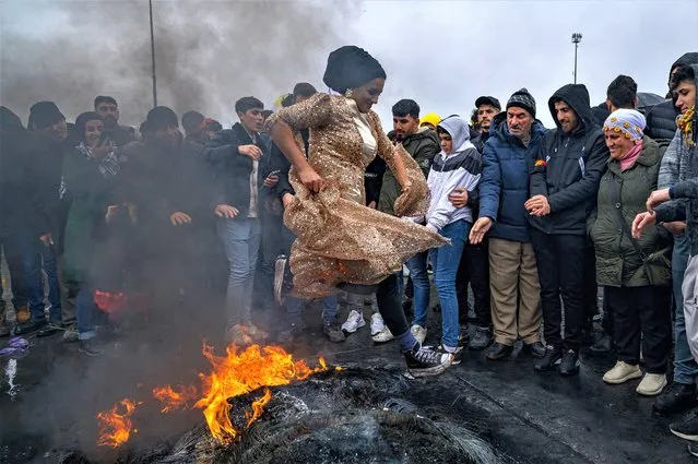 A woman jumps over a bonfire during a Kurdish celebration of Nowruz (aka Noruz or Newroz), the New Year of the Persian calendar, in Istanbul on March 19, 2022. (Photo by Yasin Akgul/AFP Photo)