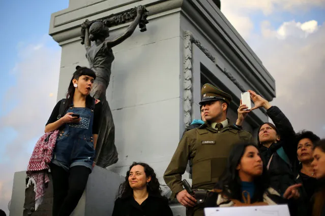 Demonstrators gather next to a police officer during a peaceful march against gender violence in Santiago, Chile, October 19, 2016. (Photo by Ivan Alvarado/Reuters)