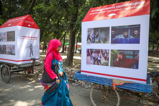 A woman walks past photographs on display at a street exhibition titled “Photographs of the Mass Uprising: July Photographs – Witness to History & a Weapon in Struggle”, held to commemorate the 1st anniversary of the uprising in Dhaka, Bangladesh, 11 August 2025. The exhibition is organized by the South Asian Media Institute “Pathshala”, showcasing photographs on rickshaw vans that will be displayed in various locations across Dhaka to honor the anniversary of the July-August mass uprising that resulted in the ousting of former premier Sheikh Hasina. (Photo by Monirul Alam/EPA)