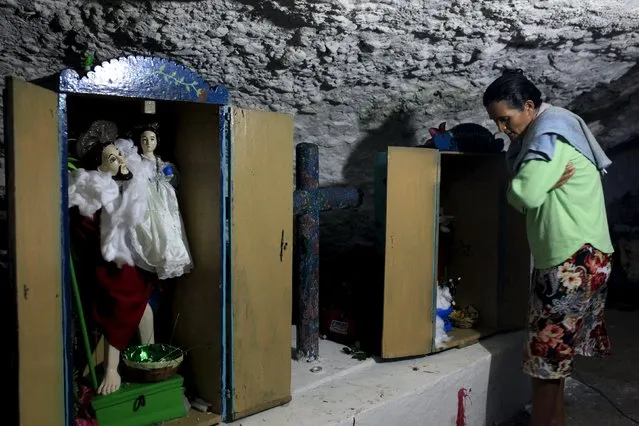 A woman prays to statues of Saint Christopher and Saint Luke at an improvised shrine in a cave during a pilgrimage by Catholic devotees known as "Cumpas", in the town of Cuishnahuat, El Salvador November 26, 2015. The Catholic people of the El Balsamo mountain range meet in the village of Cuishnahuat in November to celebrate the 'friendship' between their respective patron saints in a ceremony that has been carried out for more than 300 years, according to the government. (Photo by Jose Cabezas/Reuters)