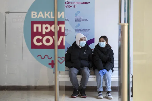 A couple wait in a queue to get a shot of Russia's Sputnik V coronavirus vaccine at a vaccination center in GUM State Department store in Moscow, Russia, Wednesday, January 20, 2021. Russia started a mass coronavirus vaccination campaign on Monday. (Photo by Pavel Golovkin/AP Photo)