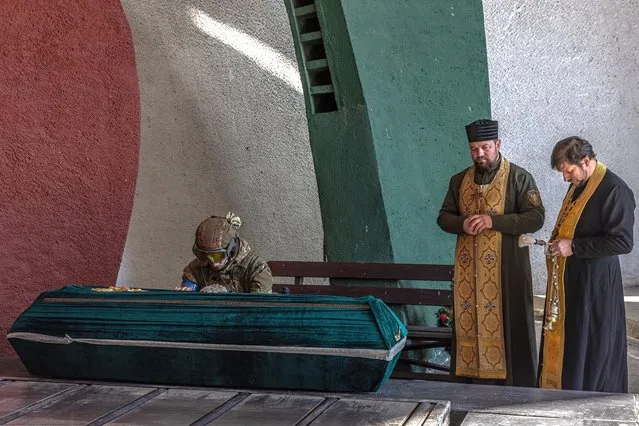 Yaroslav (C), a member of the Ukrainian military, touches the closed coffin with the body of his father Roman, a fallen Ukrainian soldier killed in the Kyiv region during the Russian invasion of Ukraine, at a cremation ceremony in a crematorium, in Kyiv, Ukraine, 15 March 2022. On 24 February Russian troops had entered Ukrainian territory in what the Russian president declared a “special military operation”, resulting in fighting and destruction in the country, a huge flow of refugees, and multiple sanctions against Russia. (Photo by Roman Pilipey/EPA/EFE)