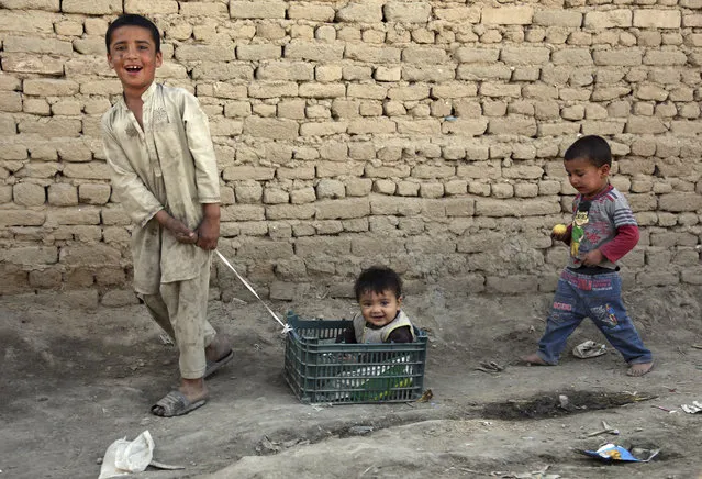 A boy pulls his little brother in a basket on the outskirts of Kabul, Afghanistan, Tuesday, May 29, 2018. (Photo by Rahmat Gul/AP Photo)