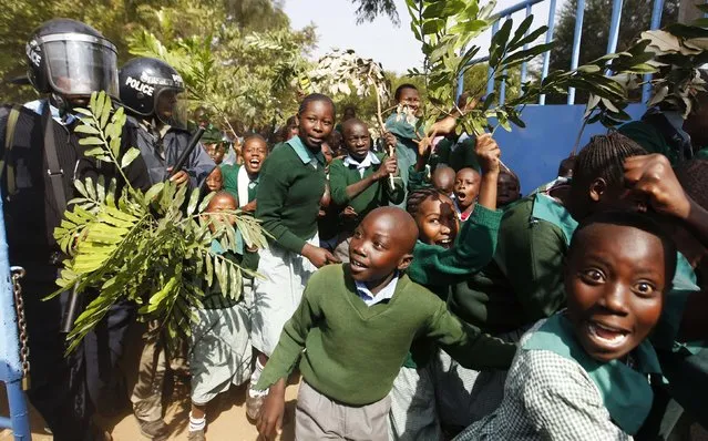 Students from Langata primary school run past riot police as they protest against a perimeter wall illegally erected by a private developer around their school playground in Kenya's capital Nairobi January 19, 2015. (Photo by Thomas Mukoya/Reuters)