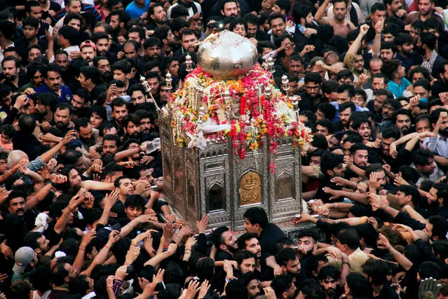 Shi'ite Muslims reach out to touch a model of a tomb, as they take part in the religious procession of Yaum-e-Ali, on 21st day of the fasting month of Ramadan marking the death anniversary of Imam Ali ibn Abi Talib, son-in-law of Prophet Mohammad, in Lahore, Pakistan June 6, 2018. (Photo by Mohsin Raza/Reuters)