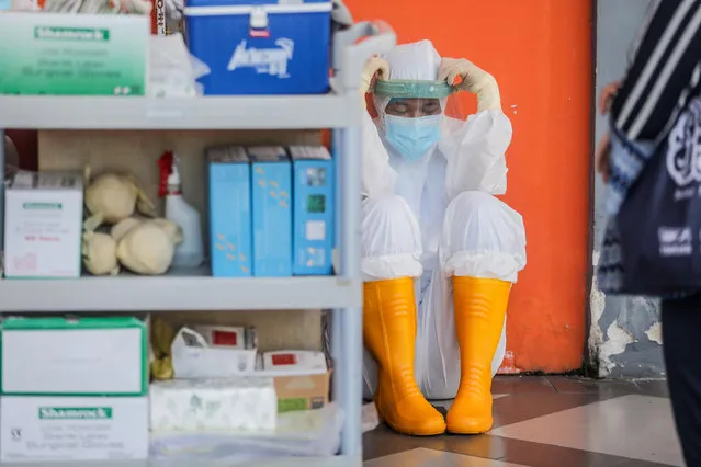A health worker in hazmat suit takes a break during a swab collection drive in Medan, North Sumatera, Indonesia, 09 February 2021. Indonesia has reported more than one million COVID-19 cases since the beginning of the pandemic, the highest number in Southeast Asia. (Photo by Dedi Sinuhaji/EPA/EFE)