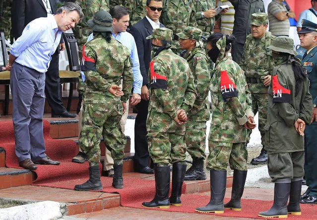 Colombia President Juan Manuel Santos (L) speaks to members of guerrilla group ELN, who have defected and handed over their weapons, at a military base in Cali July 16, 2013. Authorities said 30 rebels from Colombia's second-biggest guerrilla group, the National Liberation Army (ELN), demobilized on Tuesday in El Tambo municipality in Cauca due to military pressure in the area. (Photo by Jaime Saldarriaga/Reuters)