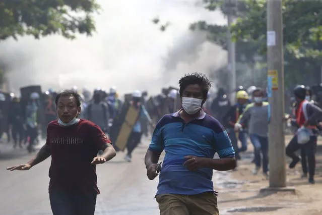 Anti-coup protesters run away when police security forces try to disperse them with tear gas in Mandalay, Myanmar, Saturday, March 13, 2021. Myanmar's military seized power Feb. 1, hours before the seating of a new parliament following election results that were seen as a rebuff to the country's generals. (Photo by AP Photo/Stringer)
