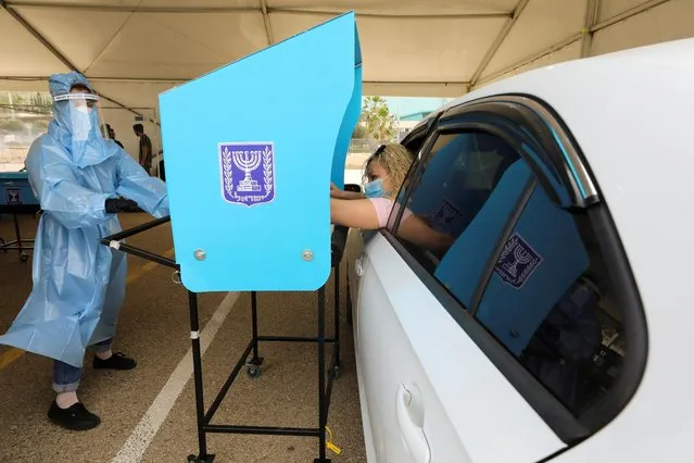 A woman votes from her car at a special mobile polling station for Israelis in quarantine or infected with the coronavirus disease (COVID-19) as Israelis begin voting in a general election, in Haifa, Israel on March 23, 2021. (Photo by Ammar Awad/Reuters)