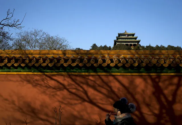 Women eat sausages as they walk past the hilltop pavilion in Jinshan Park during a blue sky day in Beijing, Tuesday, January 5, 2016. Environmental authorities in Beijing say the Chinese capital's air quality in 2015 was better than the year before despite the city's first two red alerts for pollution late in the year. (Photo by Andy Wong/AP Photo)