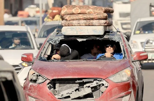 Riding in a damaged vehicle a Palestinian family flees with hundreds of other following the Israeli army's warning to leave their homes and move south before an expected ground offensive, in Gaza City on October 13, 2023. Palestinians carried belongings through the rubble-strewn streets of Gaza City on October 13, in search of refuge as Israel's army warned residents to flee immediately before an expected ground offensive in retaliation against Hamas for the deadliest attack in Israeli history. (Photo by Mahmud Hams/AFP Photo)