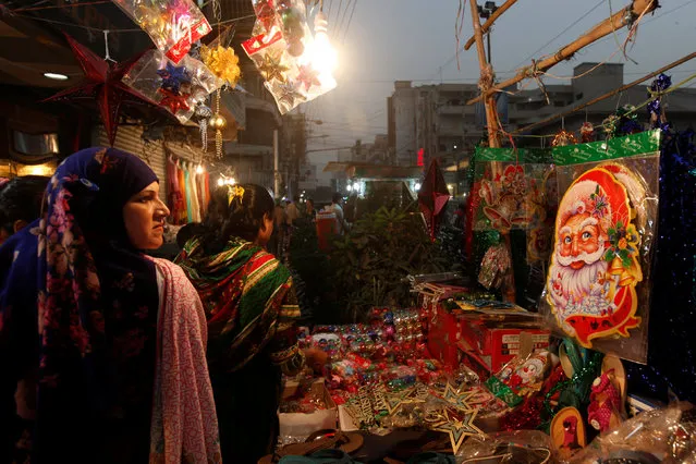 A Santa Claus decoration sticker hangs on a stall where women go through various items to buy for Christmas celebrations in Karachi, Pakistan, December 24, 2016. (Photo by Akhtar Soomro/Reuters)