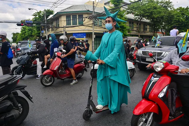 A pro-democracy protester dressed up as the Statue of Liberty rides an electric scooter during an anti-government demonstration as they commemorate the anniversary of the 1932 Siamese Revolution in Bangkok on June 24, 2021. (Photo by Lillian Suwanrumpha/AFP Photo)