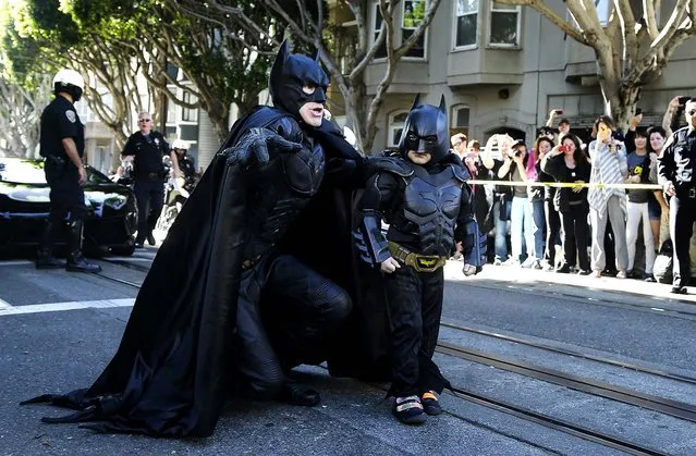 Miles Scott, dressed as Batkid, walks with Batman before saving a damsel in distress in San Francisco, on November 15, 2013. San Francisco turned into Gotham City on Friday, as city officials helped fulfill Scott's wish to be “Batkid”. Scott, a leukemia patient from Tulelake in far Northern California, was called into service on Friday morning by Police Chief Greg Suhr to help fight crime, The Greater Bay Area Make-A-Wish Foundation says. (Photo by Jeff Chiu/Associated Press)