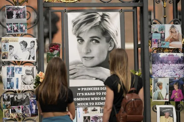 Two women look at portraits of Princess Diana and other remembrances displayed on the gates of Kensington Palace, in London, Tuesday, August 30, 2022. This week marks the 25th anniversary of Princess Diana's death in a Paris car crash. (Photo by Alastair Grant/AP Photo)
