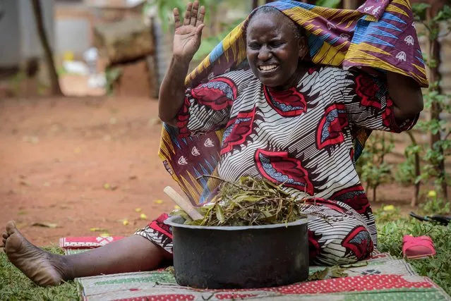 A woman reacts after covering herself to inhale steam from an infusion made from local herbs believed by her to prevent and treat the symptoms of COVID-19, in Kampala, Uganda on Tuesday, July 6, 2021. Some hospitals with COVID-19 wards are charging prohibitive sums for most Ugandans and many are now self-medicating within their homes, experimenting with everything from traditional medicine to a newly approved herbal remedy selling briskly as COVIDEX. (Photo by Nicholas Bamulanzeki/AP Photo)