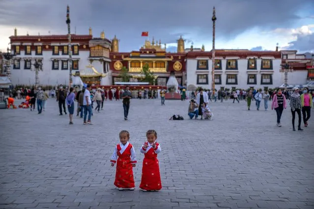 Girls stand on a square in front of the Jokhang Temple in Lhasa in western China's Tibet Autonomous Region, as seen during a government organized visit for foreign journalists, Tuesday, June 1, 2021. (Photo by Mark Schiefelbein/AP Photo)