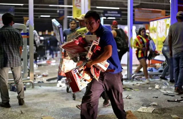 A man runs with toys as a store is ransacked by a crowd in the port of Veracruz, Mexico, Wednesday January 4, 2017. Protests over a sharp gasoline price hike erupted into looting of gas stations and stores in various parts of Mexico on Wednesday, with dozens of businesses reportedly sacked. In the Gulf coast state of Veracruz, store guards were overrun by crowds who carried off clothing, toys, food, washing machines, televisions, DVD players and refrigerators. (Photo by Ilse Huesca/AP Photo)