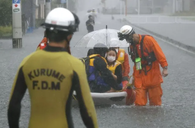 Firefighters carry stranded residents on boat in a road flooded by heavy rain in Kurume, Fukuoka prefecture, western Japan, Saturday, August 14, 2021. (Photo by Kyodo News via AP Photo)