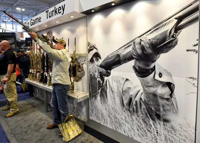 Casey Barnes looks at shotguns in the trade booth area during the National Rifle Association's annual meeting in Nashville, Tennessee, April 11, 2015. (Photo by Harrison McClary/Reuters)