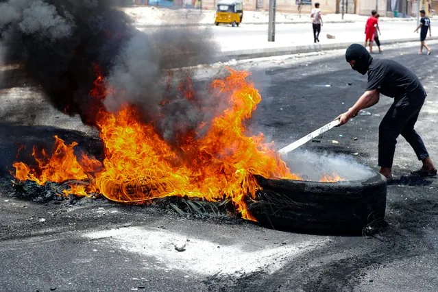 Protesters burn tires to block roads during a demonstration demanding the return of electricity in Basra, southeast of Baghdad, Iraq, Friday, July 2, 2021. A widespread power outage is hitting Iraq as temperatures reach scorching levels, affecting even affluent areas in the capital and stirring concerns of widespread unrest. (Photo by Nabil al-Jurani/AP Photo)