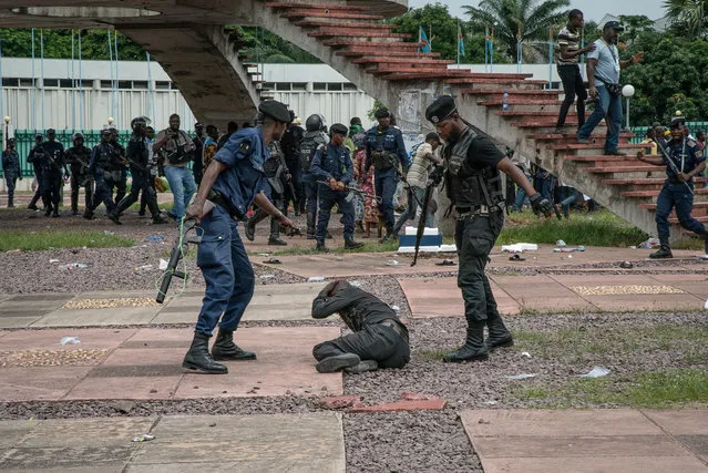A supporter of Congolese presidential candidate Martin Fayulu protect himself as policemen close on him outside the Constitutional Court in Kinshasa on January 12, 2018 as the opposition candidate filed an appeal to impose a recount of the votes in the presidential election following a suspicion of fraud. (Photo by Caroline Thirion/AFP Photo)