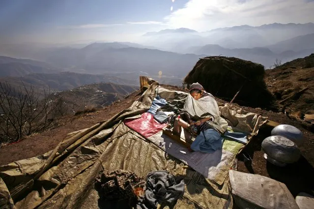 A Kashmiri earthquake survivor uses her sewing machine to sew up winter clothes, outside her shelter on the mountainous Buttlian area, some 25 km northeast of the earthquake-devastated city of Muzaffarabad in Pakistan-administered Kashmir, January 26, 2006. (Photo by Yannis Behrakis/Reuters)
