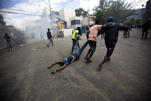 Demonstrators drag the body of a fellow protester toward police, as a form of protest after police shot into the crowd in which he died, during a demonstration demanding the resignation of Haitian President Jovenel Moise near the presidential palace in Port-au-Prince, Haiti, Tuesday, February 12, 2019. Protesters are angry about skyrocketing inflation and the government's failure to prosecute embezzlement from a multi-billion Venezuelan program that sent discounted oil to Haiti. (Photo by Dieu Nalio Chery/AP Photo)