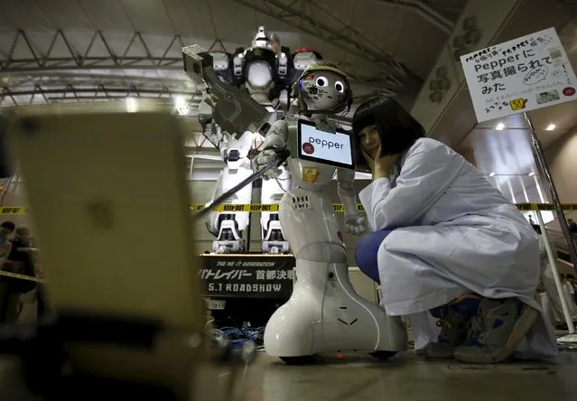 SoftBank Corp's humanoid robot named “Pepper” takes a “selfie” photo with a large robot (L in background) from the Japanese live action film series “The Next Generation – PatLabor” and its application designer (R) at a booth during Niconico Chokaigi 2015 in Makuhari, east of Tokyo, Japan April 26, 2015. (Photo by Yuya Shino/Reuters)