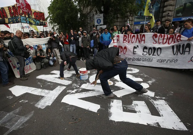 Demonstrators write down the hashtag “1M No Expo” during a protest against Expo 2015 in Milan, Italy, Thursday, April 30, 2015. (Photo by Luca Bruno/AP Photo)