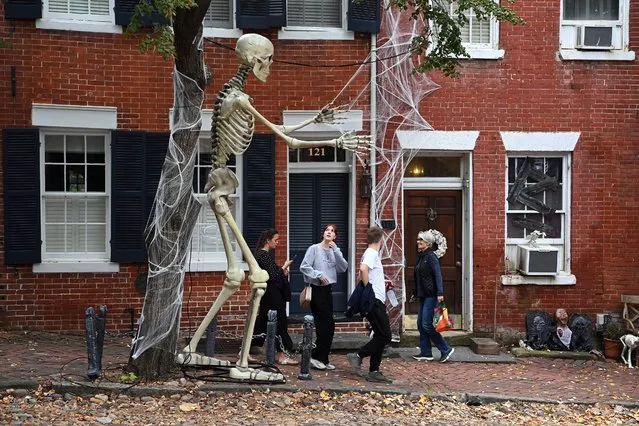 A pedestrian looks up at an oversized Halloween skeleton decoration outside of a home along Prince Street on Sunday October 10, 2021 in Alexandria, VA. (Photo by Matt McClain/The Washington Post)