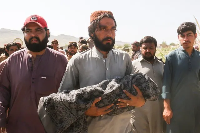 A man carries the body of a child, who died following an earthquake, during a funeral in Harnai, Balochistan, Pakistan, October 7, 2021. (Photo by Naseer Ahmed/Reuters)
