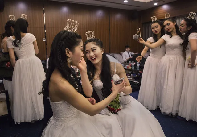Debutantes from a local academy laugh as they get ready to take part in the Vienna Ball at the Kempinski Hotel on March 19, 2016 in Beijing, China. The ball, which is an event organized by the luxury Kempinski Hotel chain and the City of Vienna, brings together both Chinese and foreign members of the capital's elite class. Despite a slowing economy, private wealth has soared in China after decades of rapid growth. A record number of high net worth individuals and families has fuelled a market for luxury goods, services, and events catering to China's burgeoning elite class. (Photo by Kevin Frayer/Getty Images)