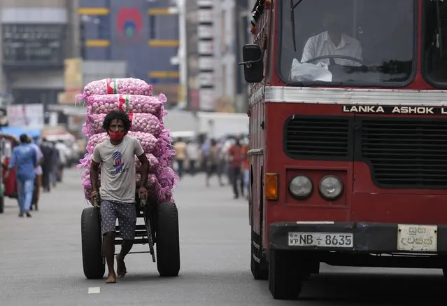 A Sri Lankan laborer pulls his cart loaded with sacks of garlic after easing of restrictions that were imposed to curb the spread of the coronavirus in Colombo, Sri Lanka, Friday, October 1, 2021. (Photo by Eranga Jayawardena/AP Photo)