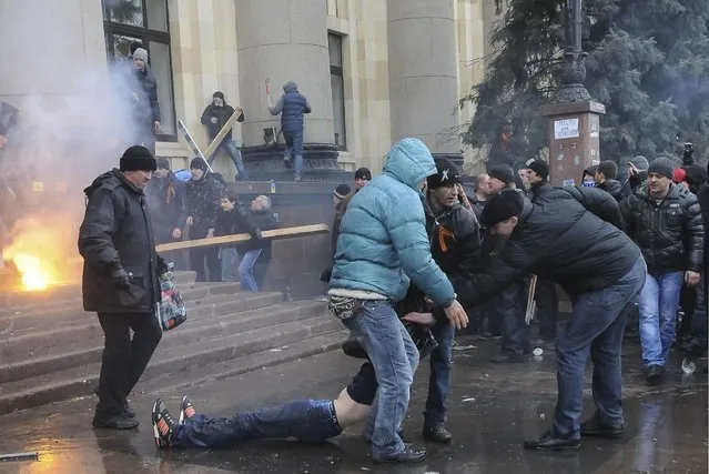 Pro-Russian protesters drag a wounded man during clashes with supporters of Ukraine's new government in central Kharkiv March 1, 2014. (Photo by Reuters/Stringer)