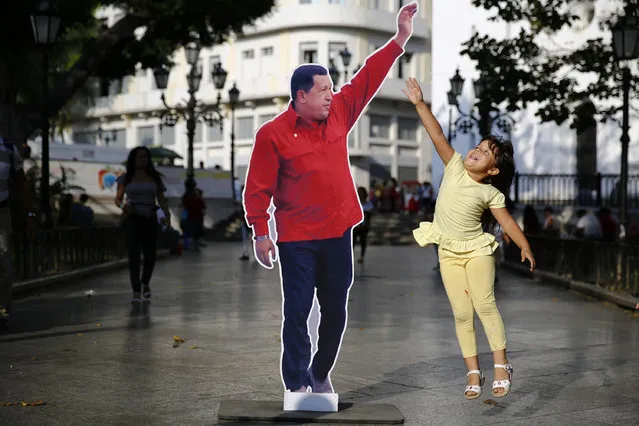 A girl jumps next to a picture of late Venezuela's president Hugo Chavez at Plaza Bolivar in Caracas March 9, 2014. Followers of Chavez are commemorating the first anniversary of his death this week, a sad but welcome distraction for his successor who has faced a month of violent protests. (Photo by Jorge Silva/Reuters)