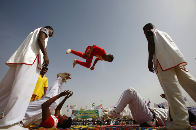 Acrobats perform during a rally organised during the visit of Sudanese president in the town of Zalingei, capital of Central Darfur state on April 3, 2016. Sudanese president Omar al-Bashir started a tour of Darfur on April 1, 2016 ahead of a referendum on whether to keep the conflict-torn western area as five states or to create one united region. Bashir – who is wanted over war crimes allegations in Darfur – said he is holding the vote under a 2011 agreement between Khartoum and some of the rebel groups that have been battling his forces for more than a decade. (Photo by Ashraf Shazly/AFP Photo)