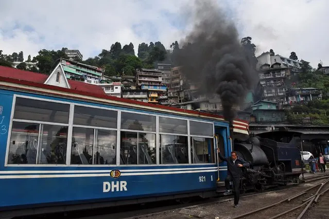 A man climbs down a Darjeeling Himalayan Railway train, which runs on a 2 foot gauge railway and is a UNESCO World Heritage Site, at a station in Darjeeling, India, June 24, 2019. (Photo by Ranita Roy/Reuters)