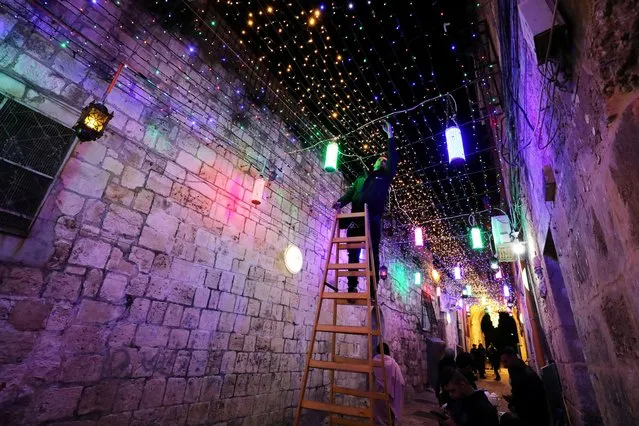 A man sets lights for decoration in an alley in Jerusalem's Old City as part of the preparation for the holy Muslim month of Ramadan as coronavirus disease (COVID-19) restrictions ease around the country on April 11, 2021. (Photo by Ammar Awad/Reuters)