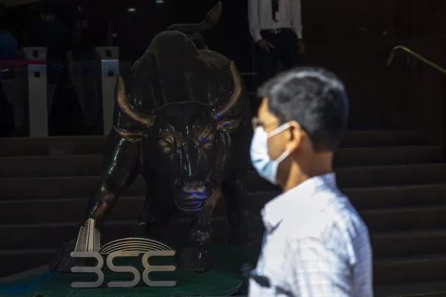A man walks near a bronze statue of a bull outside the Bombay Stock Exchange (BSE) in Mumbai, India, Tuesday, February 1, 2022. Indian Prime Minister Narendra Modi's government on Tuesday announced a series of investments to shore up spending in infrastructure projects in its annual budget designed to spur growth and popularity just days ahead of key state elections. (Photo by Rafiq Maqbool/AP Photo)