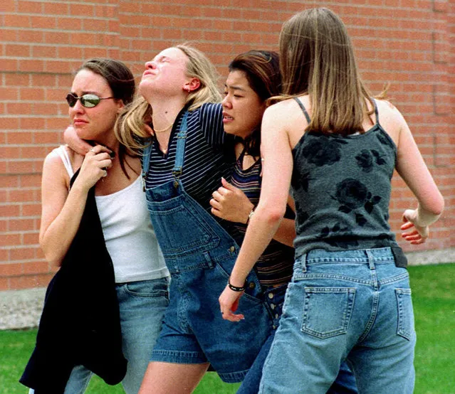 In this April 20, 1999, file photo, women head to a library near Columbine High School where students and faculty members were evacuated after two gunmen went on a shooting rampage in the school in the Denver suburb of Littleton, Colo. Twelve students and one teacher were killed in a murderous rampage at the school on April 20, 1999, by two students who killed themselves in the aftermath. (Photo by Kevin Higley/AP Photo/File)