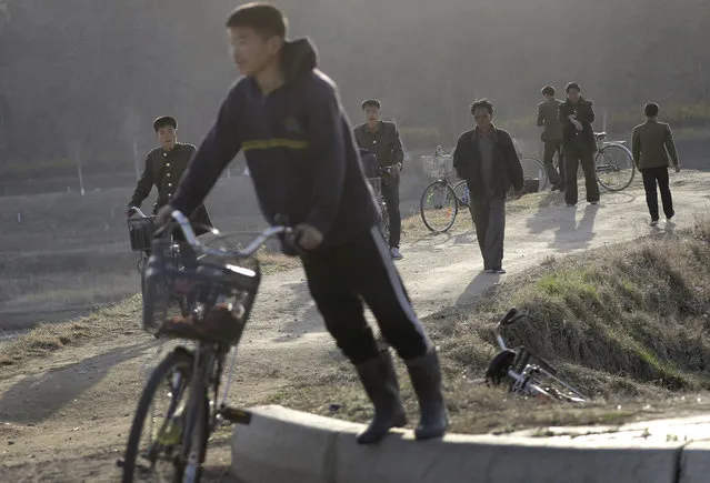 North Korean men walk, some push their bicycles along a highway at the end of a work day Tuesday, April 11, 2017, in Pyongyang, North Korea. (Photo by Wong Maye-E/AP Photo)