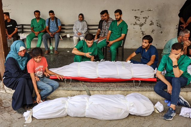 Medical staffers at the Ahli Arab Hospital mourn by the shrouded body of their colleague, a nurse who was killed during Israeli bombardment the previous night at the Shati refugee camp, at the hospital premises in Gaza City on June 14, 2024 amid the ongoing conflict in the Palestinian territory between Israel and Hamas. (Photo by Omar Al Qatta/AFP Photo)