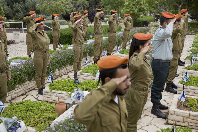 Israeli soldiers salute after placing small flags on the grave of fallen soldiers on the eve of memorial Day in Kiryat Shaul military cemetery in Tel Aviv, Israel, Tuesday, May 10, 2016. (Photo by Ariel Schalit/AP Photo)