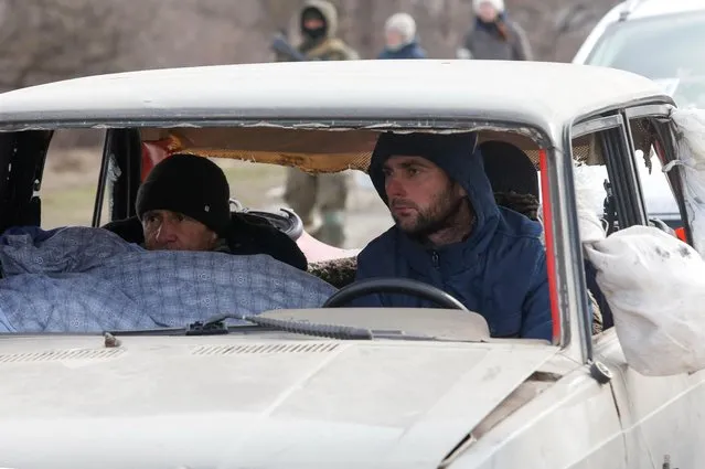 Evacuees fleeing Ukraine-Russia conflict sit in a damaged car as they wait in a line to leave the besieged southern port city of Mariupol, Ukraine on March 17, 2022. (Photo by Alexander Ermochenko/Reuters)