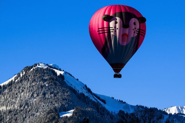 A hot-air balloon flies over the Swiss Alps during the 44th International Hot Air Balloon Festival in Chateau-d'Oex, Switzerland, Saturday, January 20, 2024. (Photo by Jean-Christophe Bott/Keystone via AP Photo)