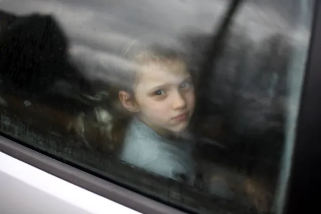 An Ukrainian child looks through the window of a car stuck in traffic, as her family drives towards the Medyka-Shehyni border crossing between Ukraine and Poland while fleeing the conflict in their country, near the Ukrainian village of Tvirzha, some 20km from the border, on February 28, 2022. The UN human rights chief said on February 28, 2022 that at least 102 civilians, including seven children, had been killed in Ukraine since Russia launched its invasion five days ago, warning the true numbers were likely far higher. (Photo by Daniel Leal/AFP Photo)
